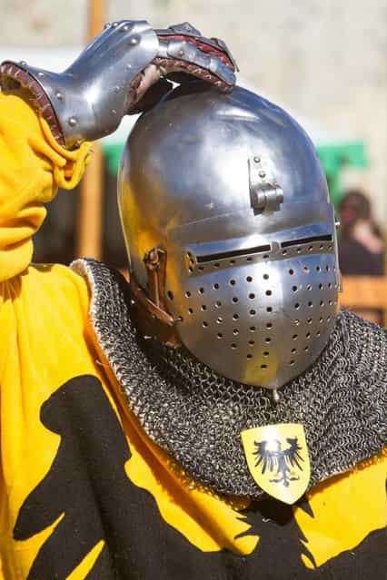 A German contestant adjusts his helmet during the [Battle of Nations] in Aigues-Mortes, southern France, Friday, May 10, 2013 where Middle Ages fans attend the historical medieval battle competition. The championship will be attended by 22 national teams, which is twice the number it was last year. The battle lasts until May 12. (Photo by Philippe Farjon/AP Photo)