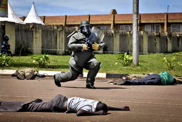 A bomb defusal expert carries a mock explosive device during a counter-terrorist training exercise at Nambole Stadium on the outskirts of Kampala, Uganda, on May 8, 2013. Police officers from the member countries of the Eastern Africa Police Chiefs Cooperation Organisation (EAPCCO) are taking part in a joint multi-national field exercise aimed at testing their response to potential terrorist incidents. (Photo by Stephen Wandera/Associated Press)