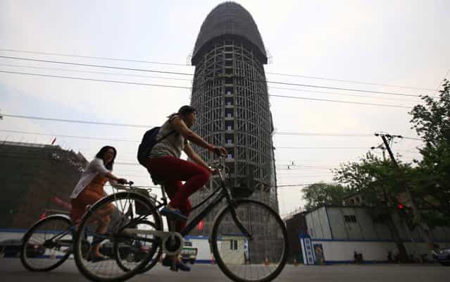 People ride past the unfinished office building of People's Daily, the official newspaper of the communist party of China, in Beijing, May 8, 2013. Some Chinese bloggers ridiculed that the building's outline, which they claim resembled the male genital, matched perfectly with the China Central Television (CCTV) tower that has been nicknamed [Big Underpants]. (Photo by Petar Kujundzic/Reuters)