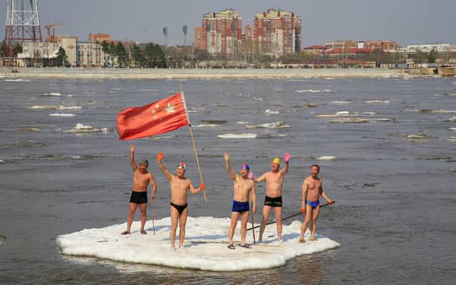 Winter swimmers wave on a piece of drifting ice with a Chinese national flag on the Amur River, in the Chinese border city of Heihe, Heilongjiang province May 6, 2013. (Photo by China Daily/Reuters)