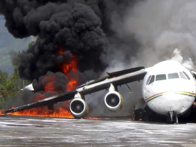 Smoke billows from a British-made BAe 146 cargo plane that caught fire while being unloaded at the airport in Wamena, Papua province, Indonesia, Wednesday, May 8, 2013. An official said that the plane caught fire after a drum of oil fell from the aircraft and somehow sparked the fire. (Photo by AP Photo)
