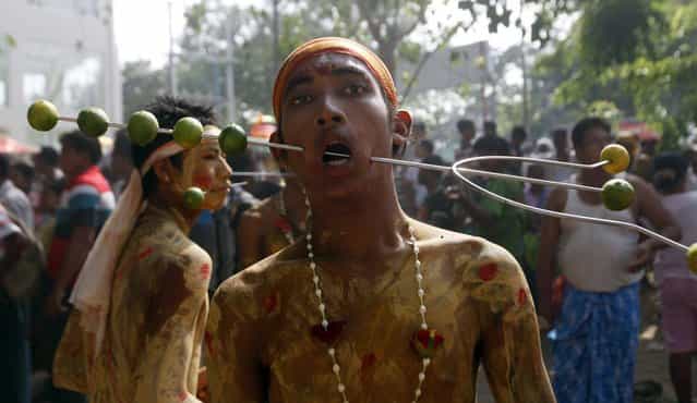 Myanmar Hindu devotees stands with his mouth pierced with a metal stick while waiting to walk on burning embers during a traditional Hindu fire festival in Yangon, Myanmar, Sunday, May 5, 2013. (Photo by Khin Maung Win/AP Photo)