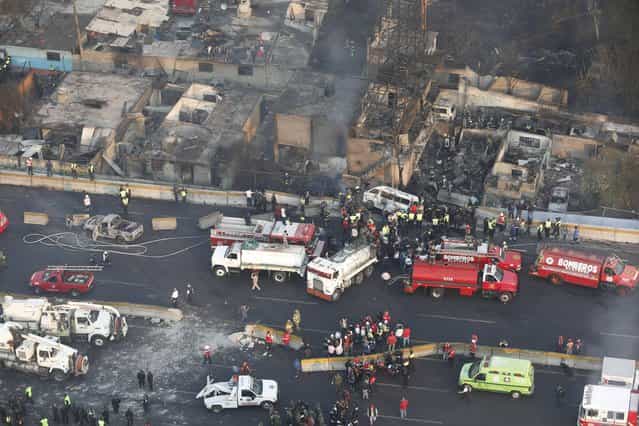 Aerial view shows first responders working next to destroyed homes and vehicles after a gas tanker truck exploded on a highway in the Mexico City suburb of Ecatepec early Tuesday, May 7, 2013. The blast killed and injured dozens, according to the Citizen Safety Department of Mexico State. Officials did not rule out the possibility the death toll could rise as emergency workers continued sifting through the charred remains of vehicles and homes built near the highway on the northern edge of the metropolis. (Photo by AP Photo)