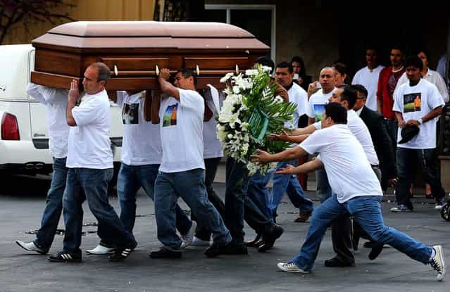 Pallbearers carry the casket of Ricardo Portillo as two people catch flowers that fell off the casket as it is carried to a local church for his funeral in Salt Lake City, on May 8, 2013. Portillo, a soccer official, was punched by a teenage player after issuing a yellow card during a game last week. He died of his injuries this past weekend. (Photo by George Frey/Getty Images)
