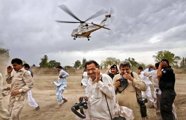 People rush for cover as Pakistan's former Prime Minister Nawaz Sharif leaves in a helicopter after addressing an election rally near Peshawar, Pakistan, on May 7, 2013. (Photo by Mohammad Sajjad/Associated Press)