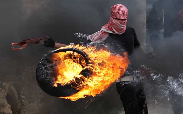 A Palestinian sets fire to a tyre during clashes between hundreds of Palestinians and Israeli soldiers outside the Ofer prison after a march marking the 65th Nakba day or [Day of Catastrophe] in Betunia near the West Bank city of Ramallah, on May 15, 2013. (Photo by Abbas Momani/AFP Photo)