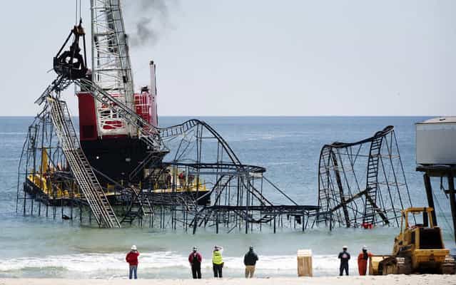 A barge moves into position as workers prepare to remove the Star Jet rollercoaster, on May 14, 2013, that has been in the ocean for six months after the Casino Pier it was built on collapsed when superstorm Sandy hit Seaside Heights, New Jersey. (Photo by Lucas Jackson/Reuters)
