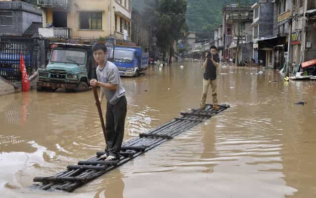 A journalist (R) records a video on a raft as a man paddles along flooded street after heavy downpours hit Jianghua Yao Autonomous County, Hunan province, on May 16, 2013. (Photo by Reuters/Stringer)
