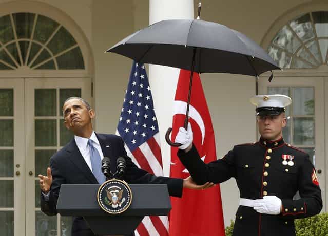 U.S. President Barack Obama checks to see if he still needs the umbrella held by a U.S. Marine to protect him from the rain during a joint news conference with Turkish Prime Minister Recep Tayyip Erdogan in the Rose Garden of the White House in Washington, May 16, 2013. (Photo by Jason Reed/Reuters)