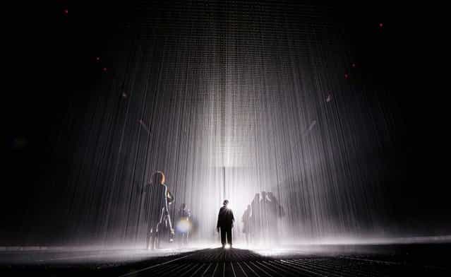 Visitors gather in the new [Rain Room] installation at the Museum of Modern Art (MoMA) in Manhattan, on May 15, 2013. The 5,000 square-foot installation creates a field of falling water that stops in the area where people walk through, allowing them to remain dry. The piece, created by Random International, releases a 260-gallon per minute shower around visitors. (Photo by Mario Tama/Getty Images)
