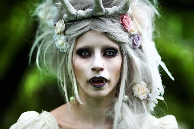 A woman in vampire make-up attends the traditional park picnic on the first day of the annual Wave-Gotik Treffen, or Wave and Goth Festival, in Leipzig, Germany, on May 17, 2013. The four-day festival, in which elaborate fashion is a must, brings together over 20,000 Wave, Goth and steam punk enthusiasts from all over the world for concerts, readings, films, a Middle Ages market and workshops. (Photo by Marco Prosch/Getty Images)