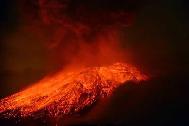A cloud of ash belches out of Mexico’s Popocatepetl volcano, some 55 km from Mexico City, as seen from Cholula, in the Mexican central state of Puebla, on May 15, 2013. The volcano spewed a new column of ash late Tuesday, with some of the material falling on three towns while glowing rocks landed on the towering mountain’s slope. Authorities have raised the alert level to [Yellow Phase Three,] the fifth of a seven-stage warning system, restricting access to an area of 12 km around the volcano while preparing evacuation routes and shelters. (Photo by Arturo Andrade/Getty Images)