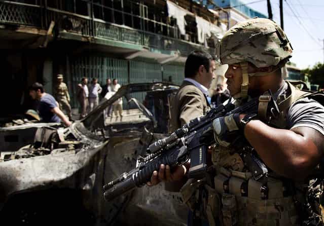 A U.S. soldier arrives at the scene where a suicide car bomber attacked a NATO convoy in Kabul, Afghanistan, on May 16, 2013. A Muslim militant group, Hizb-e-Islami, claimed responsibility for the early morning attack, killing many in the explosion, police and hospital officials said. The powerful explosion rattled buildings on the other side of Kabul and sent a pillar of white smoke into the sky. (Photo by Anja Niedringhaus/Associated Press)