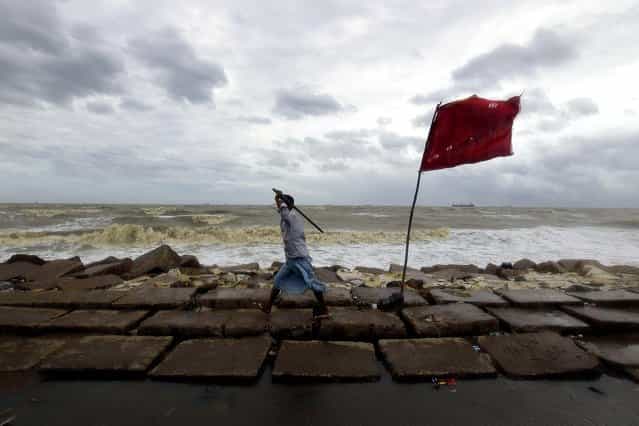 A volunteer walks along the Bay of Bengal coast to evacuate people in Chittagong, Bangladesh, on May 16, 2013. Cyclone Mahasen struck the southern coast of Bangladesh on Thursday, lashing remote fishing villages with heavy rain and fierce winds that flattened mud and straw huts and forced the evacuation of more than 1 million people. (Photo by A. M. Ahad/Associated Press)