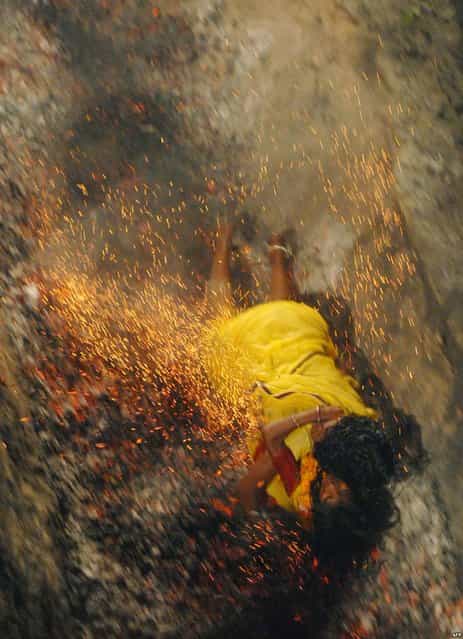 An Indian Hindu devotee falls on burning coals while holding her daughter during a coal run at the Maa Maariamma Mela in Jalandhar, India. The devotees run on fire after fasting for seven days to prove their devotion. The mother and daughter were both injured. (Photo by Shammi Mehra/AFP Photo)