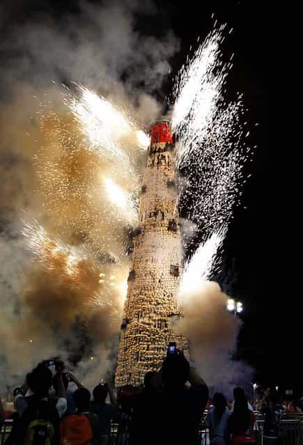 Fireworks explode on the bun tower after the Bun Scrambling contest, on May 18, 2013. The Bun Festival is a traditional event celebrating the islanders' deliverance from famine centuries ago and is meant to placate ghosts and restless spirits. (Photo by Kin Cheung/AP Photo)