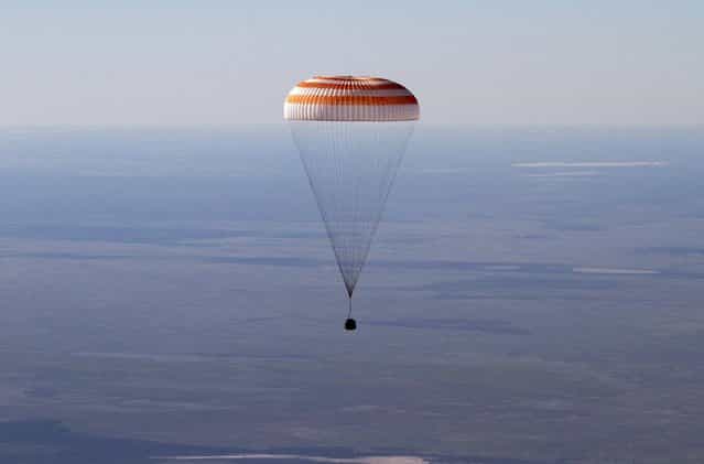 The Russian Soyuz space capsule, carrying U.S. astronaut Thomas Marshburn, Russian cosmonaut Roman Romanenko and Canadian astronaut Chris Hadfield, descends some 150 kilometers (94 miles) southeast of the town of Dzhezkazgan in central Kazakhstan, Tuesday, May 14, 2013. The Soyuz space capsule carrying a three-man crew returning from a five-month mission to the International Space Station landed safely Tuesday on the steppes of kazakhstan. (Photo by Sergei Remezov/AP Photo)