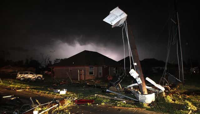 Lightning strikes from a storm illuminate the sky above where damage is strewn about the street and light pole after a tornado in Cleburne, Texas, on May 15, 2013. Cleburne Mayor Scott Cain early Thursday declared a local disaster as schools canceled classes amid the destruction. (Photo by Tom Fox/The Dallas Morning News)