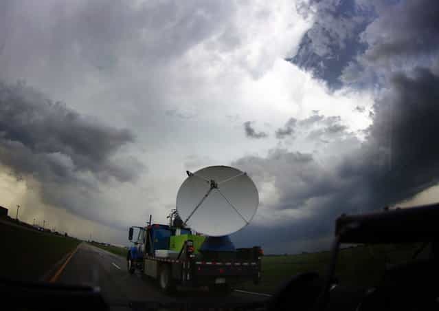 A National Oceanic and Atmospheric Administration (NOAA)'s mobile doppler radar mounted on the back of a truck tracks a tornadic thunderstorm passing over Clearwater, in Kansas May 19, 2013. A massive storm front swept north through the central United States on Sunday, hammering the region with fist-sized hail, blinding rain and tornadoes, including a half-mile wide twister that struck near Oklahoma City. News reports said at least one person had died. The picture was taken through a car window. (Photo by Gene Blevins/Reuters)