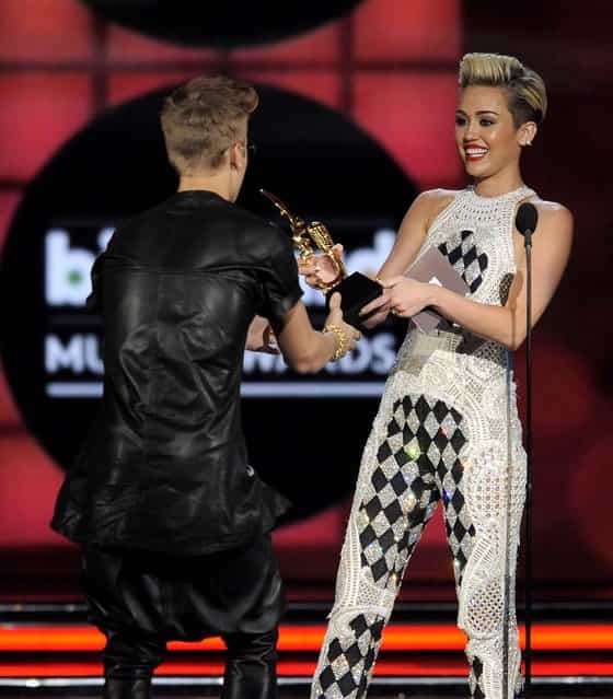 Miley Cyrus presents the award for top male artist to Justin Bieber. (Photo by Chris Pizzello/Invision)
