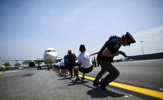 Members of the London Metropolitan Police Service tug an Airbus A320 jet for 100 feet (30.48m) during a race at John F. Kennedy International Airport in New York, May 20, 2013. The fourth annual race [Plane Pull] is a fundraising competition to benefit the charity Joining Against Cancer in Kids. (Photo by Eduardo Munoz/Reuters)