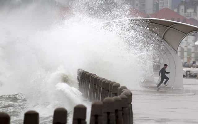 A man runs away as waves whipped up by winds surge past a barrier onto a seaside road in Yantai, Shandong Province, China, on May 27, 2013. (Photo by Reuters/Stringer)