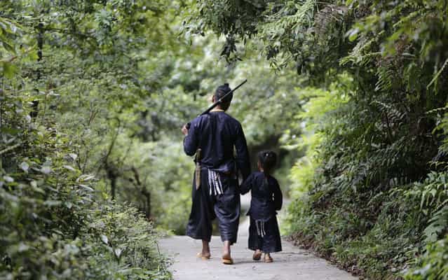 Ethnic Miao man Gun Yuangu, 45, walks with his grandson in the village of Basha in Congjiang county, Guizhou province, May 28, 2013. The village, an old ethnic Miao settlement with a population of 2,200, is believed to be the last community authorized by the Chinese government to keep guns. Although people in Basha no longer subsist on hunting, guns and gunpowder pots have become part of their traditional dress, while firing towards the sky is seen as a ritual to welcome guests, according to local media. (Photo by Jason Lee/Reuters)