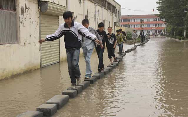 Students were forced to walk on bricks laid out along a road after the rain, at a school in Shangqiu, on May 28, 2013. The 150 metre long road has always flooded after rain in recent years. A project to build a raised road for the students’ safety in rain was scheduled last year but has not yet beeen carried out. (Photo by Reuters/Stringer)