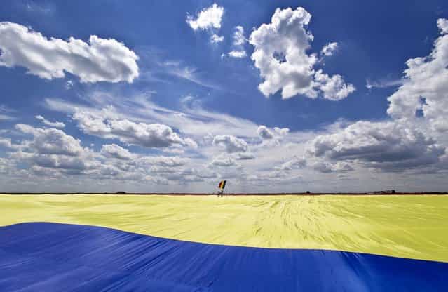 The Guinness World Record was set when the flag, which organizers said measured 349.4 meters by 226.9 meters, was successfully unfurled. It took about 200 people several hours to unfurl the five-ton flag of Romania, on May 27, 2013. (Photo by Vadim Ghirda/Associated Press)