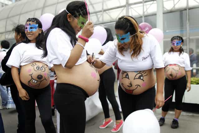 Pregnant women paint their bellies before an event to celebrate [Healthy Maternity Week] in Lima May 30, 2013. About 300 pregnant women participated in celebrations organized by a local hospital seeking to create awareness of healthcare for expectant mothers. (Photo by Enrique Castro-Mendivil/Reuters)