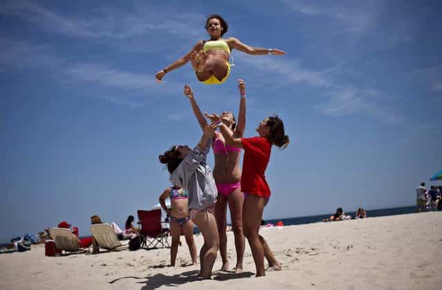Emilie Sullivan is thrown into the air by her friends as they play on the first weekend of Jersey Shore beaches re-opening to the public, in Seaside Heights, New Jersey, on May 27, 2013. The region continues to recover and rebuild after Hurricane Sandy devastated parts of the coastline. (Photo by Kena Betancur/Getty Images)