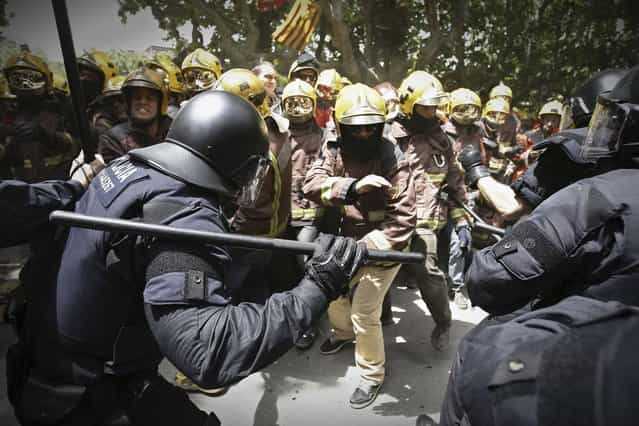 Riot police charge at firefighters during a protest against austerity measures in front of the Catalunya Parliament in Barcelona, Spain, Wednesday, May 29, 2013. The European Union moved away from its focus on tough austerity Wednesday when it gave France, Spain and four other member states more time to bring their budget deficits under control to support their economies. (Photo by Paco Serinelli/AP Photo)