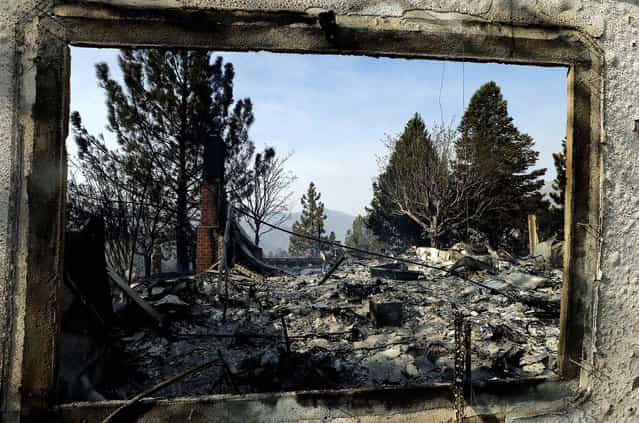 A window frames the view of one of at least five structures destroyed or severely damaged in Lake Hughes. Erratic wind fanned a blaze in the Angeles National Forest to nearly 41 square miles on June 2, 2013, after fast-moving flames triggered the evacuation of nearly 1,000 homes in Lake Hughes and Lake Elizabeth. (Photo by Reed Saxon/Associated Press)