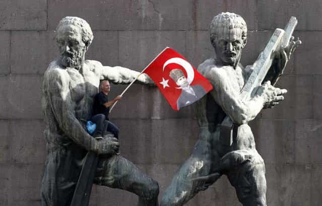 A demonstrator waves Turkey's national flag as he sits on a monument during a protest against Turkey's Prime Minister Tayyip Erdogan and his ruling AK Party in central Ankara June 2, 2013. Erdogan accused Turkey's main secular opposition party on Sunday of stirring a wave of anti-government protests, as tens of thousands regrouped in Istanbul and Ankara after a lull and trouble flared again in the capital. Police used tear gas on protesters in Ankara but the clashes were relatively minor compared with major violence in Turkey's biggest cities on the previous two days. (Photo by Umit Bektas/Reuters)