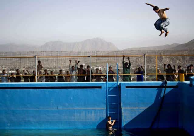 A young Afghan man jumps from a diving board into a swimming pool on a hill overlooking Kabul, Afghanistan, on May 17, 2013. The swimming pool build by the Soviets more then 30 years ago has rarely been used caught instead in the middle of decades of war. (Photo by Anja Niedringhaus/AP Photo)