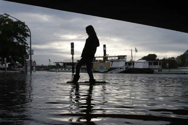 A woman with rubber boots walks across a flooded street under a bridge in Dresden, Germany, Monday, June 3, 2013. Heavy rainfalls cause flooding along rivers and lakes in Germany, Austria, Switzerland and the Czech Republic. (Photo by Markus Schreiber/AP Photo)