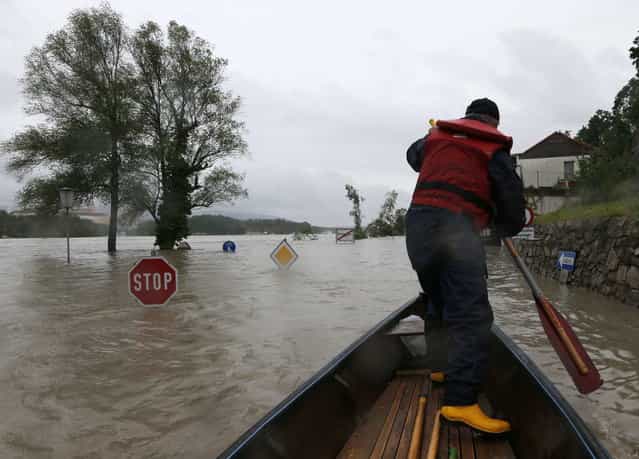 A member of the emergency services travels by boat along a flooded street in the centre of the Austrian village of Emmersdorf, about 100 km (62 miles) west of Vienna June 3, 2013. Torrential rain in Tyrol, Salzburg, Upper and Lower Austria caused heavy flooding over the weekend, forcing people to evacuate their homes. (Photo by Leonhard Foeger/Reuters)