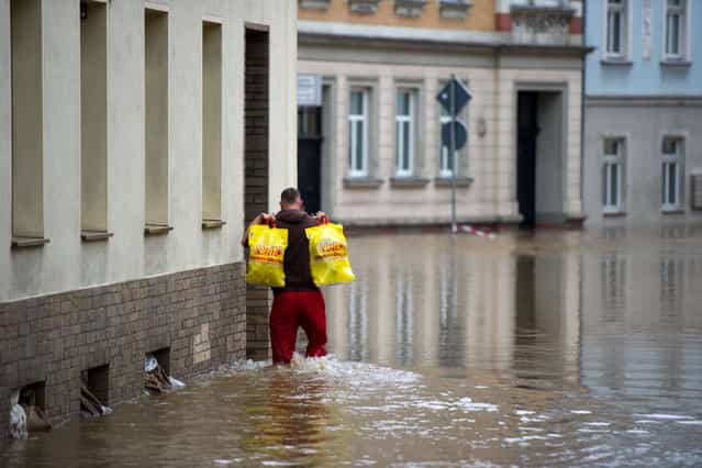 A man carrying plastic bags makes his way through a overfloode street in Doebeln, eastern Germany, on June 3, 2013. Parts of the eastern and southern Germany were flooded due to heavy and ongoing rainfalls. (Photo by Arno Burgi/AFP Photo)