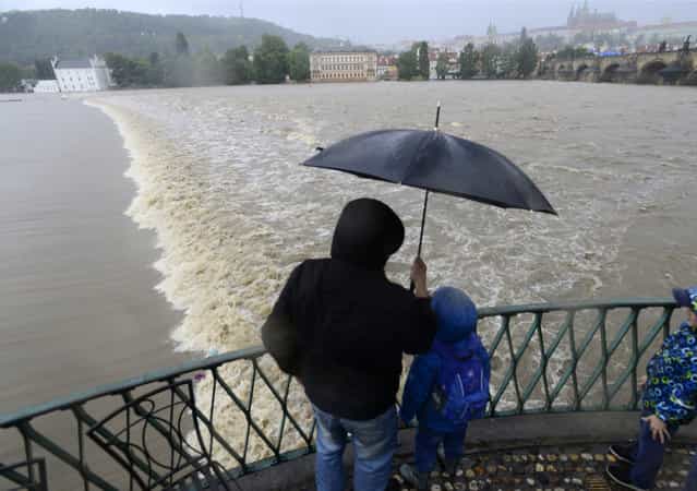 A family watches the swollen Vltava river in the center of Prague, Czech Republic, Sunday, June 2, 2013. Heavy rainfalls cause flooding along rivers and lakes in Germany, Austria, Switzerland and the Czech Republic. (Photo by Roman Vondrous/AP Photo/CTK)
