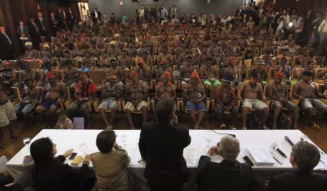 Minister of the General Secretariat of the Presidency of Brazil, Gilberto Carvalho (C), speaks to Munduruku Indians during a meeting at the Planalto Palace in Brasilia, June 4, 2013. President Dilma Rousseff's government sought on Tuesday to defuse mounting conflicts with indigenous groups over its decision to stop setting aside farm land for Indians and plans to build more hydroelectric dams in the Amazon. The government flew 144 Munduruku Indians to Brasilia for talks to end a week-long occupation of the controversial Belo Monte dam on the Xingu river, a huge project aimed at feeding Brazil's fast-growing demand for electricity. (Photo by Ueslei Marcelino/Reuters)