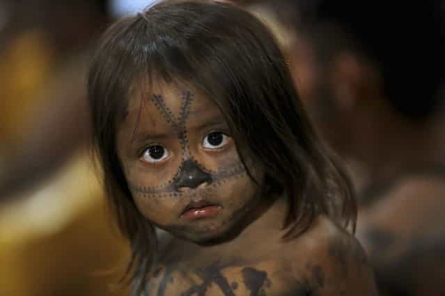 A Munduruku Indian child is pictured at the Planalto Palace, where a meeting with Minister of the General Secretariat of the Presidency of Brazil Gilberto Carvalho was being held with other Munduruku Indians, in Brasilia, June 4, 2013. President Dilma Rousseff's government sought on Tuesday to defuse mounting conflicts with indigenous groups over its decision to stop setting aside farm land for Indians and plans to build more hydroelectric dams in the Amazon. The government flew 144 Munduruku Indians to Brasilia for talks to end a week-long occupation of the controversial Belo Monte dam on the Xingu river, a huge project aimed at feeding Brazil's fast-growing demand for electricity. (Photo by Ueslei Marcelino/Reuters)