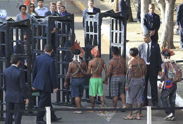 Munduruku Indians pass through a metal detector as they arrive for a meeting with the Minister of the General Secretariat of the Presidency, Gilberto Carvalho, at the Planalto Palace in Brasilia, June 4, 2013. President Dilma Rousseff's government sought on Tuesday to defuse mounting conflicts with indigenous groups over its decision to stop setting aside farm land for Indians and plans to build more hydroelectric dams in the Amazon. The government flew 144 Munduruku Indians to Brasilia for talks to end a week-long occupation of the controversial Belo Monte dam on the Xingu river, a huge project aimed at feeding Brazil's fast-growing demand for electricity. (Photo by Ueslei Marcelino/Reuters)