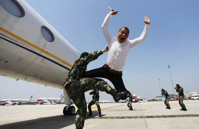 A paramilitary policeman knocks down a man role-playing as a plane hijacker during an anti-terrorism drill at Nanjing Lukou International Airport in Nanjing, Jiangsu province June 3, 2013. (Photo by Reuters/China Daily)