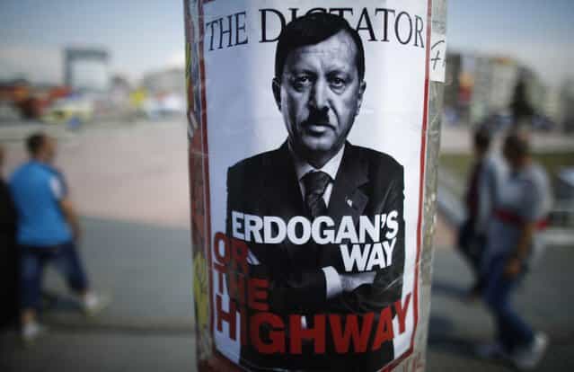 People walk past a poster depicting Turkish Prime Minister Tayyip Erdogan that has been pasted by demonstrators at Taksim Square in Istanbul June 5, 2013. Protesters clashed with police across Turkey overnight despite an apology for police violence from the deputy prime minister designed to halt an unprecedented wave of protest against Prime Minister Tayyip Erdogan. Pro-government newspapers signalled a softening of Ankara's line in the absence of Erdogan, who flew off on a state visit to north Africa on Monday night after a weekend of rioting critics said were inflamed by his denunciations of protesters. (Photo by Stoyan Nenov/Reuters)