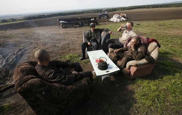 Inmates sit on a sofa and armchairs while having a meal during a work break on an agrarian field of a penal colony settlement, some 40 km (25 miles) northeast of Russia's Siberian city of Krasnoyarsk, June 6, 2013. Some 250 inmates, who were given life sentences and committed to forced labour works in security prison camps, operate on regional penitentiary system agrarian fields and at farms, according to the regional penitentiary system official representatives. Every hour inmates are obliged to sign a document during working hours as part of a regular controlling check, conducted by prison guards. (Photo by Ilya Naymushin/Reuters)