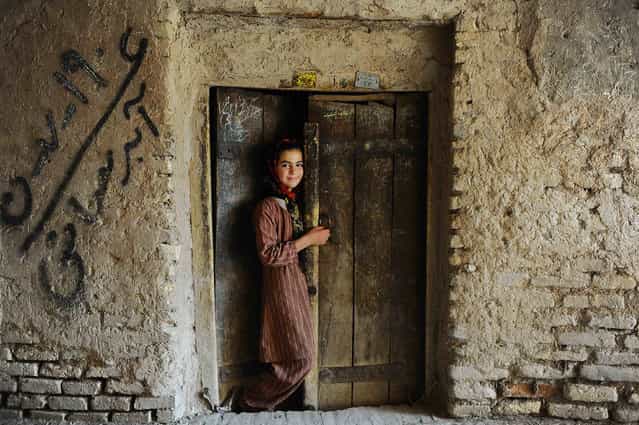 An Afghan girl stands in the doorway of her house in the old sector of Herat on June 5, 2013. Over a third of Afghans are living in abject poverty, as those in power are more concerned about addressing their vested interests rather than the basic needs of the population, a UN report said. (Photo by Aref Karimi/AFP Photo)