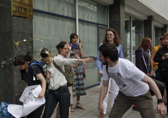 A radical Orthodox believer (R) throws an egg at gay rights activists during a protest against a proposed new law termed by the State Duma as [against advocating the rejection of traditional family values] in central Moscow June 11, 2013. Russian police detained more than 20 gay rights activists involved in a [kissing protest] on Tuesday outside parliament where lawmakers were preparing to pass a bill banning homosexual [propaganda]. (Photo by Maxim Shemetov/Reuters)