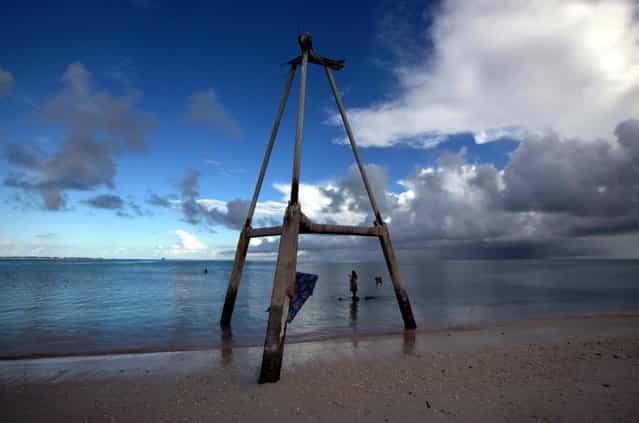 Binata Pinata stands on top of a rock underneath an old tower as she waits for her husband Kaibakia to hand her the fish he is catching, on Bikeman islet, located off South Tarawa in the central Pacific island nation of Kiribati May 25, 2013. (Photo by David Gray/Reuters)
