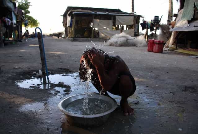 A boy washes himself with water from a well outside his home in the village of Antebuka located on South Tarawa in the central Pacific island nation of Kiribati May 25, 2013. (Photo by David Gray/Reuters)