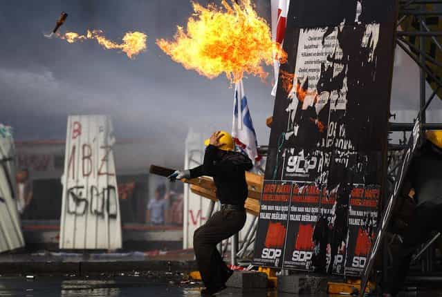 A protester throws a petrol bomb towards policemen during clashes in Taksim Square in Istanbul, on June 11, 2013. Hundreds of police in riot gear forced through barricades in Istanbul's central Taksim Square early Tuesday, pushing many of the protesters who had occupied the square for more than a week into a nearby park. (Photo by Kostas Tsironis/Associated Press)